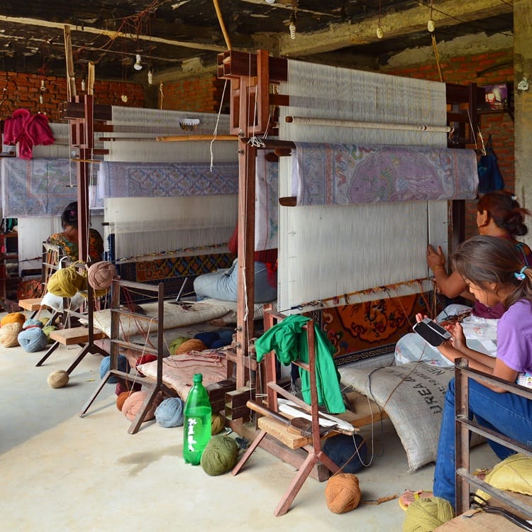 Weaver making rugs on Aryahita looms